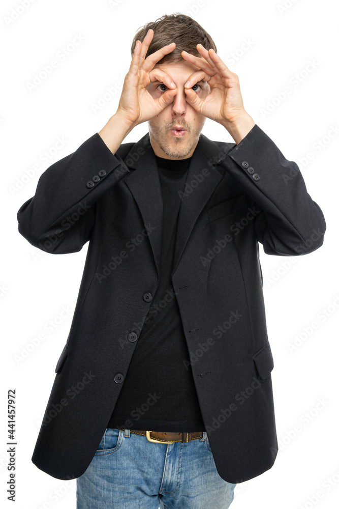 Young handsome tall slim white man with brown hair making glasses from his hands in black blazer in blue jeans isolated on white background Young handsome tall slim white man with brown hair making glasses from his hands in black blazer in blue jeans isolated on white background