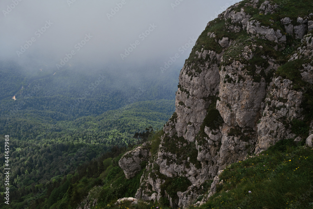 Nature and landscape of national Park in Caucasus. Cold summer day in mountains. Steep rocky mountain against background of thick black fog before rain.