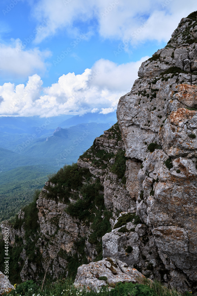 Nature and landscape of national Park in Caucasus. Cold summer day in mountains. Steep rocky mountain against background of snow capped mountains in distance on horizon.