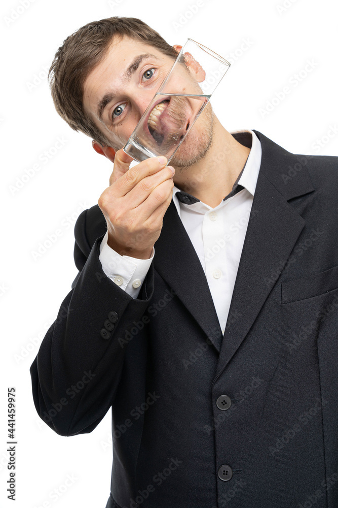 Young handsome tall slim white man with brown hair holding glass of water in front of his face isolated on white background Young handsome tall slim white man with brown hair holding glass of water in front of his face isolated on white background