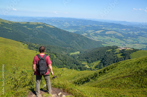 Back view of hiker with backpack and trekking sticks on top of mountain enjoying the view. Carpathian mountains, Ukraine © Dmytro