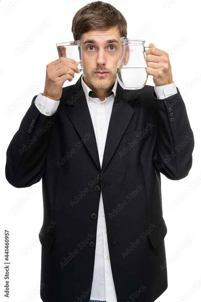 Young handsome tall slim white man with brown hair holding glass pitcher of water and glass of water isolated on white background Young handsome tall slim white man with brown hair holding glass pitcher of water and glass of water isolated on white background