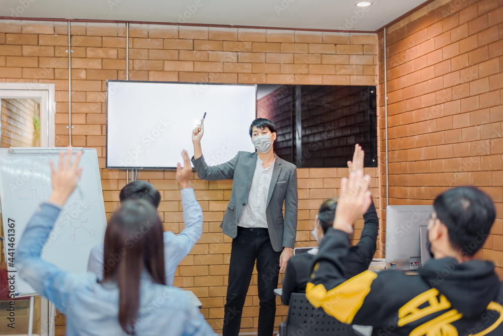 Fototapeta premium business cooperation : Young asian male coach or speaker make flip chart presentation to diverse businesspeople at meeting in office. Male tutor or trainer present project to diverse colleagues.