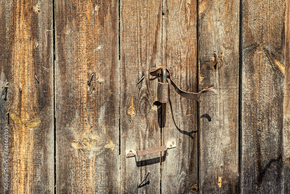 An old wooden gate with a rusty lock, background.