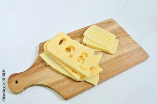 Slices of Emmental cheese and Tilsit cheese on cutting board photo