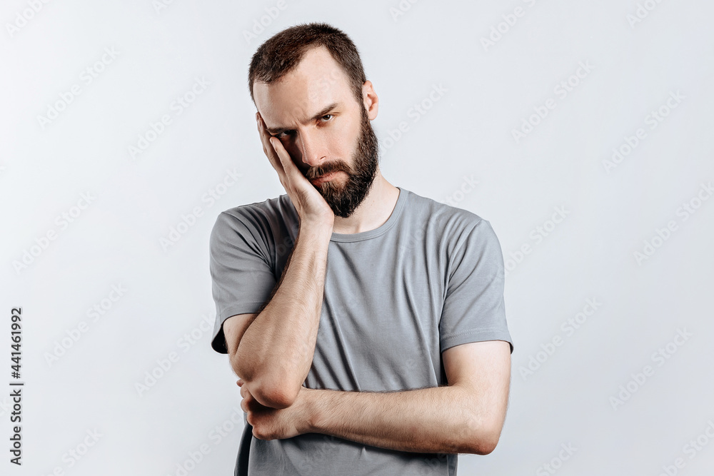 Portrait of handsome young man frowning while holding hands near head on white background with space for advertising mock up Portrait of handsome young man frowning while holding hands near head on white background with space for advertising mock up