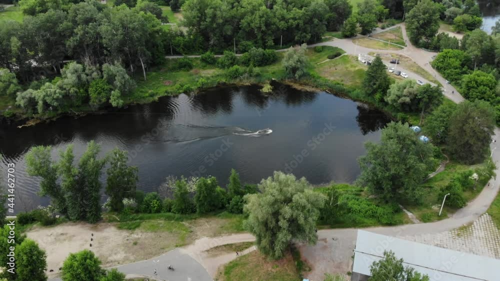 A young athlete is engaged in wakeboarding view from a drone. Extreme sport. Rest on the river. Guy rides a wakeboard shot from a drone. Athlete swims on the board A young athlete is engaged in wakeboarding view from a drone. Extreme sport. Rest on the river. Guy rides a wakeboard shot from a drone. Athlete swims on the board