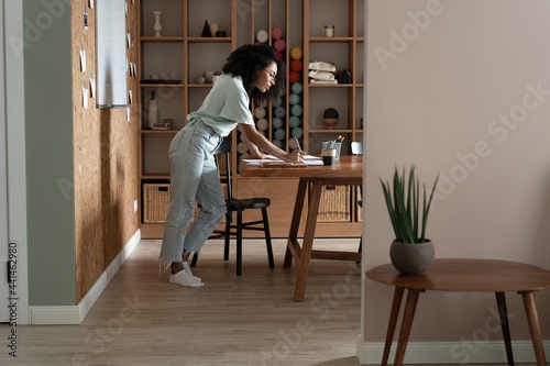Mixed-race beautiful businesswoman working with papers while standing in modern office © opolja
