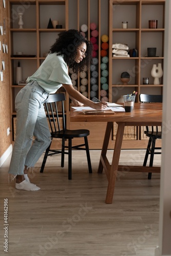 Mixed-race beautiful businesswoman working with papers while standing in modern office