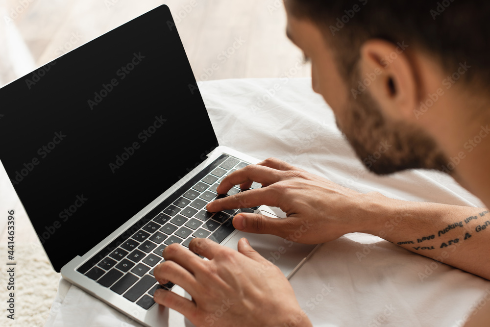 Blurred man using laptop with blank screen on white bedding Blurred man using laptop with blank screen on white bedding