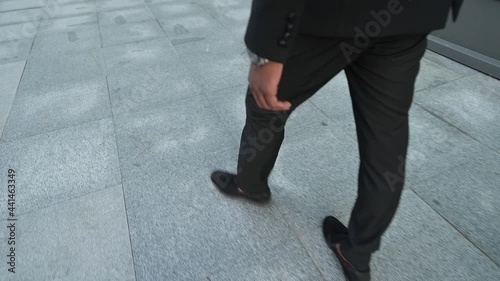 Legs of a black man walking down the street in a suit, slow motion