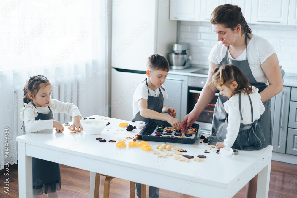 Mom teaches children to cook candy cookies. Leisure activity with children concept