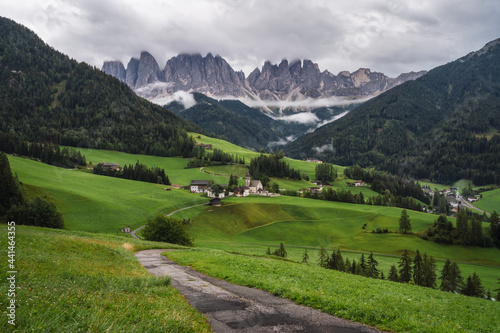 Hiking trail to St Magdalena church in Val di Funes valley, Dolomites, Italy. Furchetta and Sass Rigais mountain peaks in background