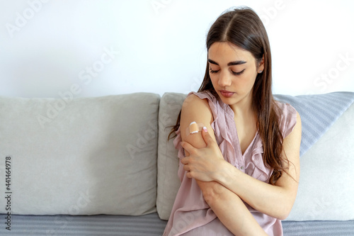 Caucasian young woman holding her shoulder in pain after getting vaccination during new strain of COVID-19. Young girl feeling uncomfortable after receives coronavirus vaccine on her arm. Copy space.