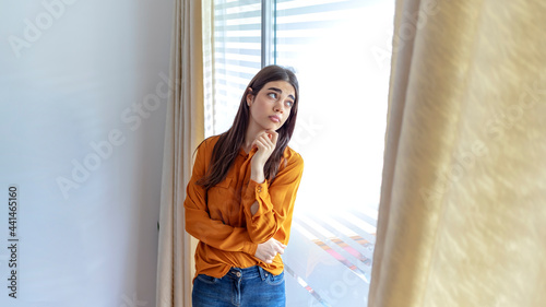 Free Download Cropped shot of a beautiful woman looking out the window at home. Sad young woman suffering from agoraphobia looking out of window. Depressed woman standing by window at home. Depressed woman at home. - GFXLoad