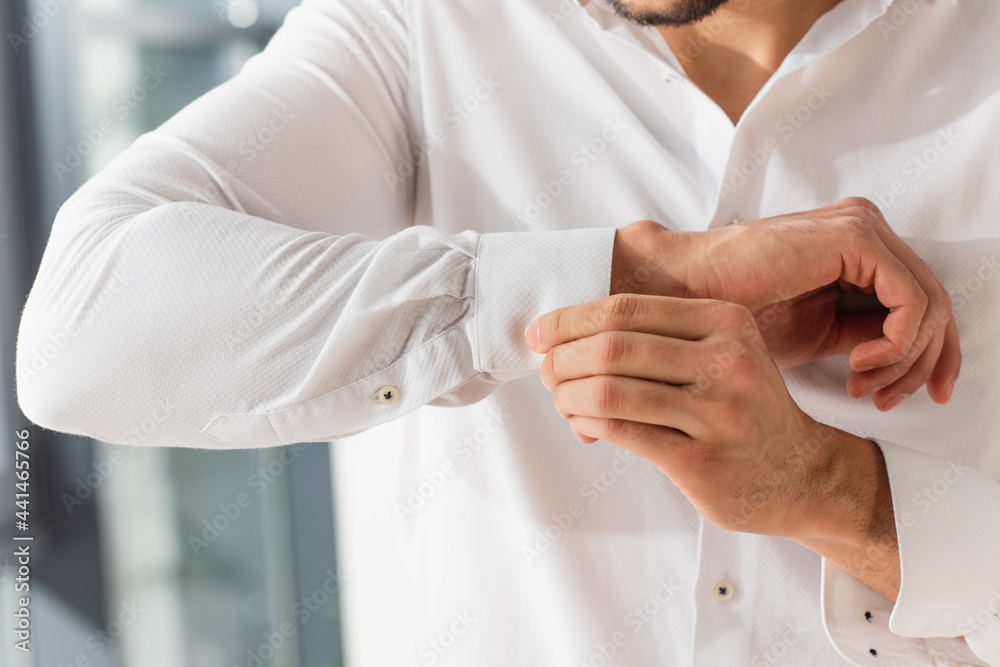 Cropped view of manager buttoning shirt while getting ready at home