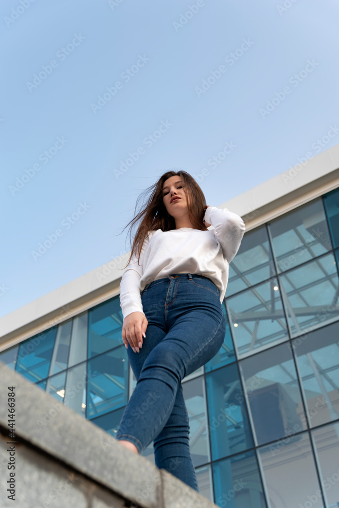Portrait of girl on the background of modern building bottom view. Vertical frame.
