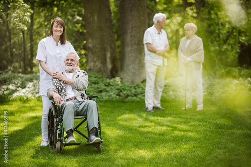Smiling caregiver with disabled man in the garden