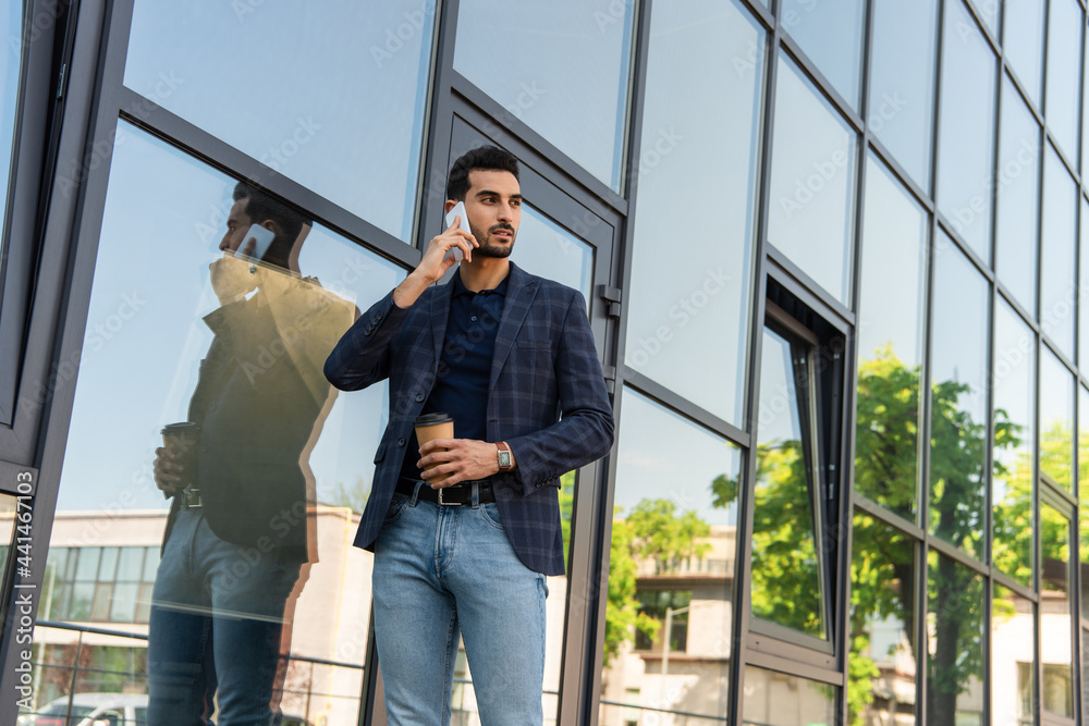 Arabian businessman talking on smartphone and holding coffee to go outdoors Arabian businessman talking on smartphone and holding coffee to go outdoors