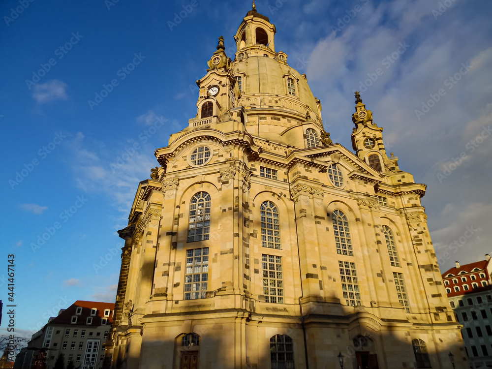 Die Dresdner Frauenkirche in leuchtend sanfter Abendsonne vor blauem Himmel auf Froschperspektive.