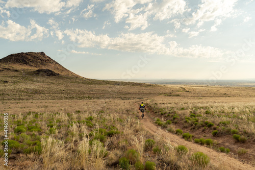 A lone cyclist on a dirt trail through a field of shrubs and brush at the foot of a small mountain, Petroglyph NM, New Mexico photo