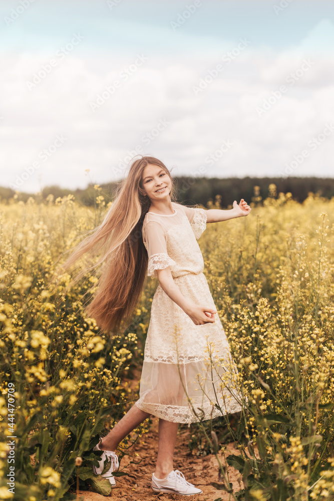 A young beautiful girl with long hair walks in a rapeseed field. Vertical A young beautiful girl with long hair walks in a rapeseed field. Vertical