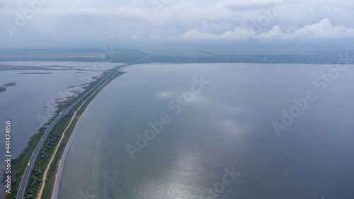 A highway that runs along a narrow spit between the sea and the estuary. Cars on the road. Aerial view.
