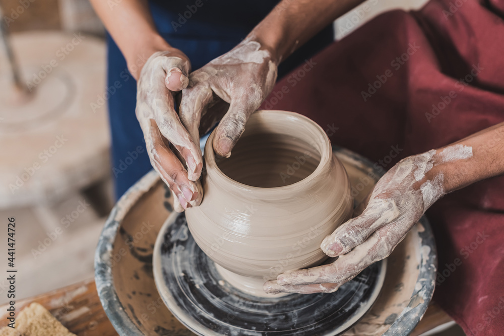 partial view of young african american couple modeling wet clay pot on wheel with hands in pottery partial view of young african american couple modeling wet clay pot on wheel with hands in pottery