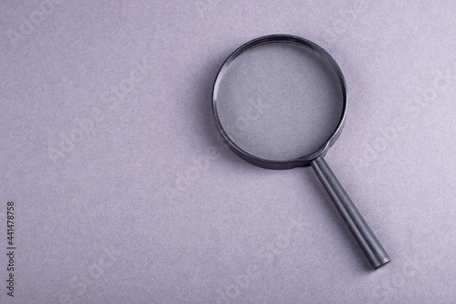 Concept information search. Magnifying glass on classic gray background. Top view. Flat lay. Trendy color.