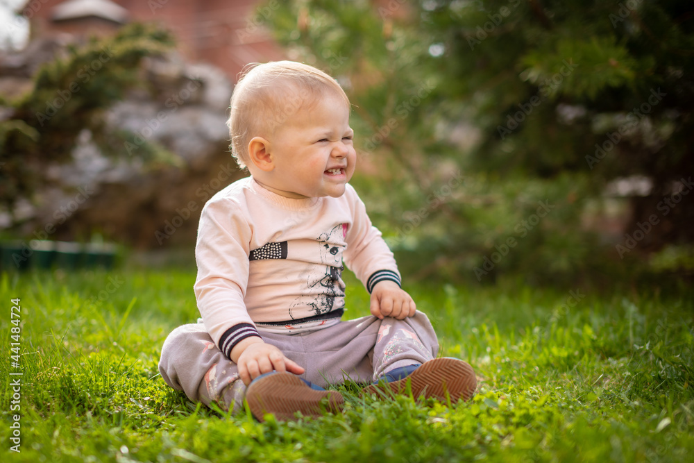 Sweet baby girl playing on green grass in park in spring time Sweet baby girl playing on green grass in park in spring time