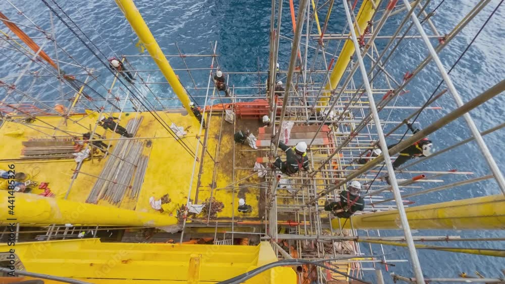 4K time lapse aerial view of contractors performing scaffold erection works at gas platform in the middle of the sea.