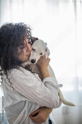 Happy curly brunette woman pet owner holding dog Jack Russell Terrier breed feeling love friendship