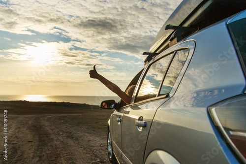 travel to the sea by car. the girl stuck out her hand. thumb as a sign of pleasure