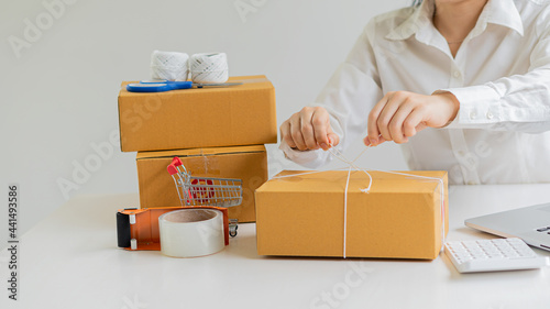 Start small business, business woman, successful SME entrepreneur. Work-at-home woman with laptop taking orders from customers with online parcel delivery. SME delivery concept and packaging