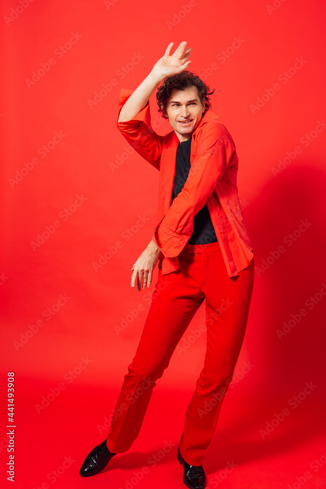 Tall handsome man dressed in red shirt posing on the red background Tall handsome man dressed in red shirt posing on the red background