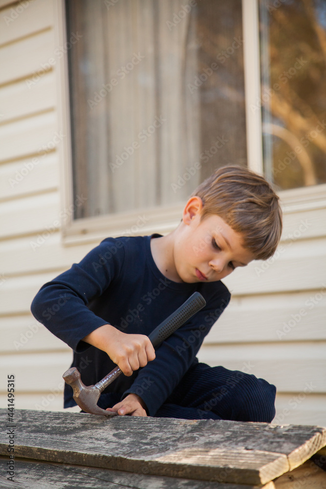 Young boy repairing cubbyhouse with nails Young boy repairing cubbyhouse with nails