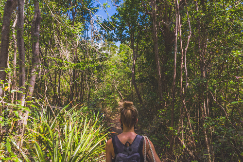 Woman walking through tropical forest path from behind