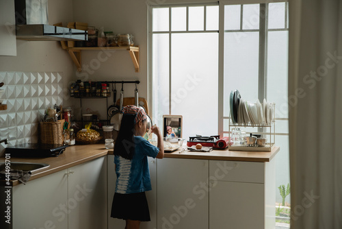 Girl 6-7years mixing flour at kitchen recording video