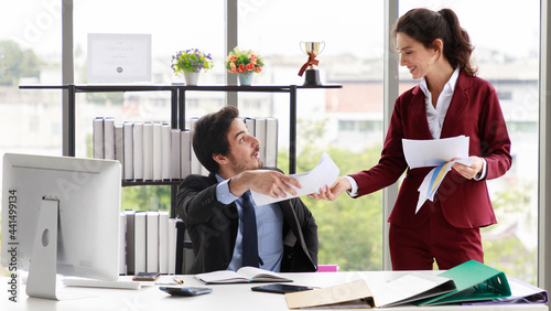 Cheerful colleagues discussing papers in office