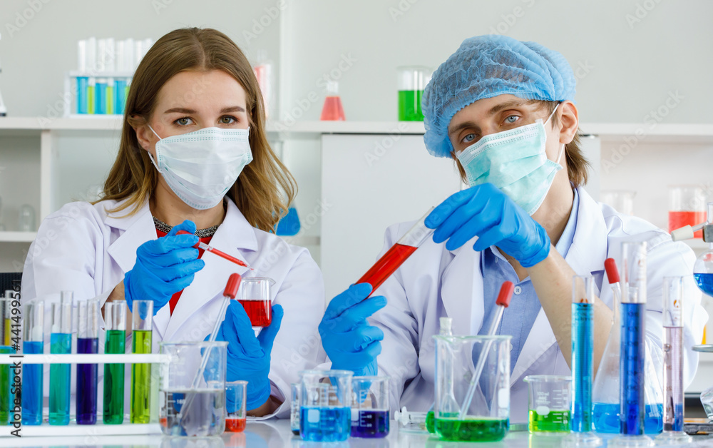 Caucasian man and woman scientist are discussing about testing results. Man hold test tube and science equipment microscope, many test tube put on table in laboratory Caucasian man and woman scientist are discussing about testing results. Man hold test tube and science equipment microscope, many test tube put on table in laboratory