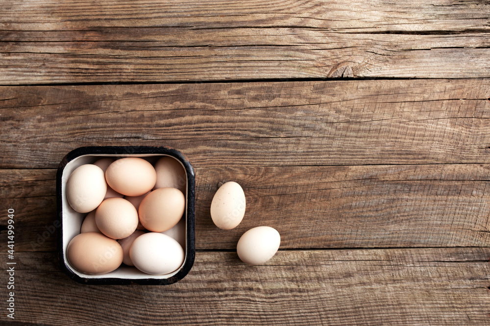 Chicken eggs in basket on wooden background. Organic household
