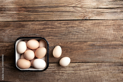 Chicken eggs in basket on wooden background. Organic household