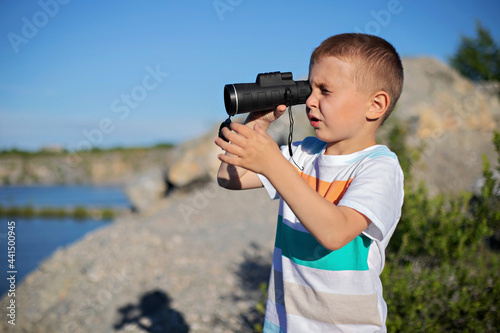 ittle boy holding binoculars and looking into the distance photo