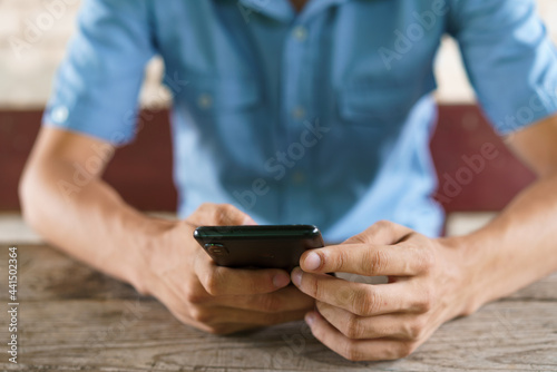 Young man sits on street at table with phone in his hand Fototapeta