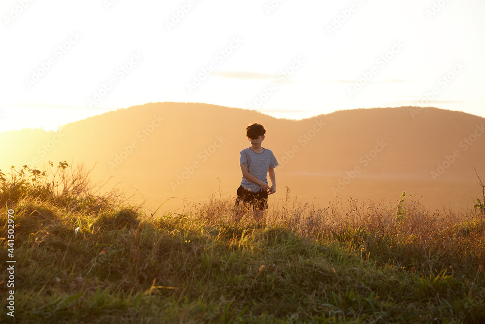 Young boy looking out to mountains at sunset Young boy looking out to mountains at sunset