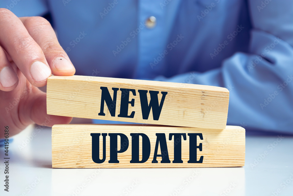 Businessman pressing his finger on the wooden cubes with the word new update. Download a new software or technology update concept. Businessman pressing his finger on the wooden cubes with the word new update. Download a new software or technology update concept.