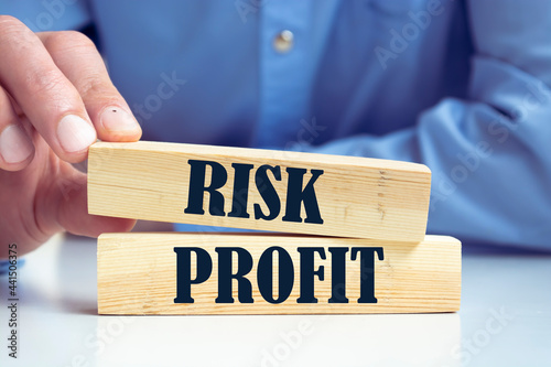 risk profit. man offers a choice of wooden blocks with the words risk and profit