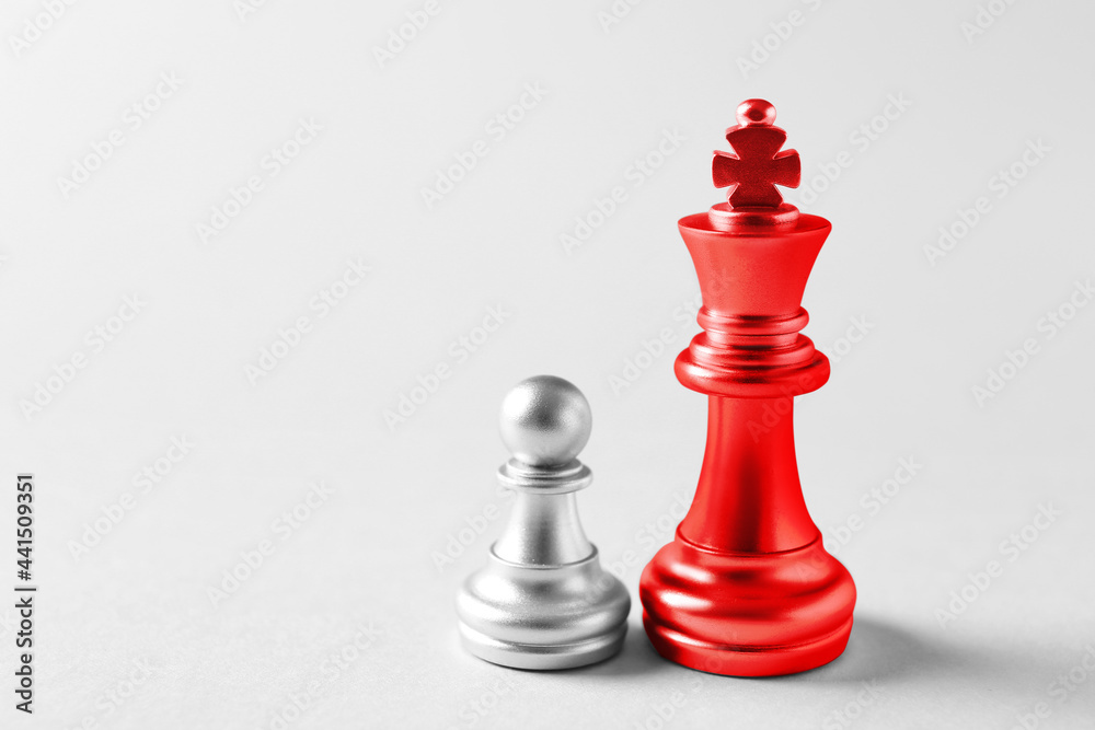 Red king and silver pawn on light background Red king and silver pawn on light background