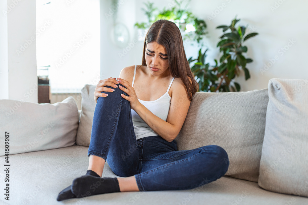 woman holding the knee with pain on sofa,health care and medical concept. woman holding the knee with pain on sofa,health care and medical concept.
