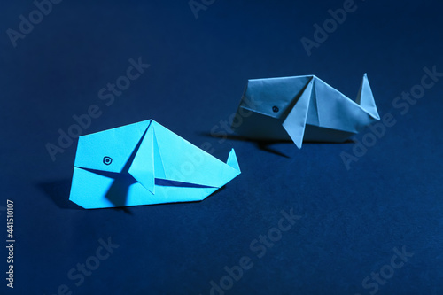Origami whales on color background  closeup. Concept of uniqueness